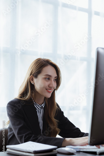 A businesswoman is checking company financial documents and using a laptop to talk to the chief financial officer through a messaging program. Concept of company financial management.