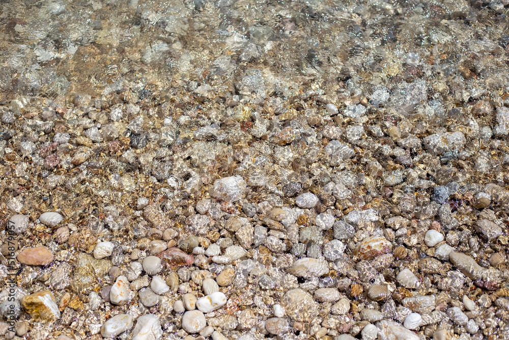 Pebble beach. Texture of clean transparent sea water with pebble bottom Pebble beach. Texture of clean transparent sea water with pebble bottom
