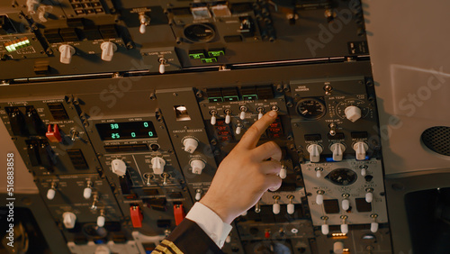 Male captain pushing dashboard buttons to start airplane engine, using control panel command to fly plane. Preparing to takeoff with aircraft jet, using aerial navigation. Close up.