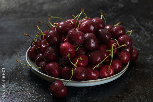 A white ceramic dish filled with cherries in the center. Dark background.