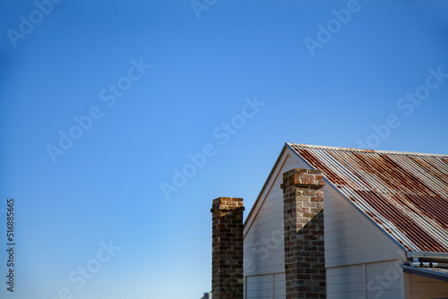 Wallpaper Mural Rusty roof and stone chimney of old building against blue sky Torontodigital.ca