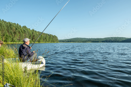 Male fisherman is standing on the riverbank with a fishing rod in his hands and catching fish. Calm outdoor recreation
