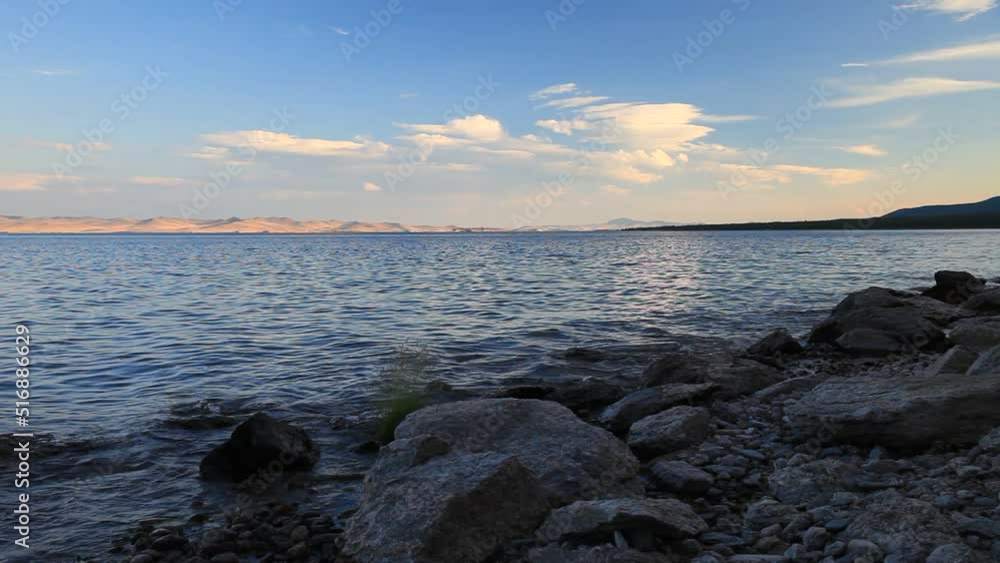 Summer landscape of Baikal lake at sunset. Pebble beach of the Small Sea with clear water on a sunny day. Traveling and hiking along the lake Summer landscape of Baikal lake at sunset. Pebble beach of the Small Sea with clear water on a sunny day. Traveling and hiking along the lake