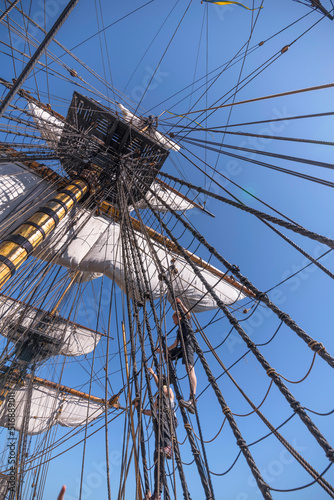 Sailors climbing the rig on the replica of the old Indian Man Götheborg, at the pier Skeppsbron in the old town Gamla Stan, for Shanghai 2023, a sunny summer day in Stockholm, Sweden 2022-07-13
