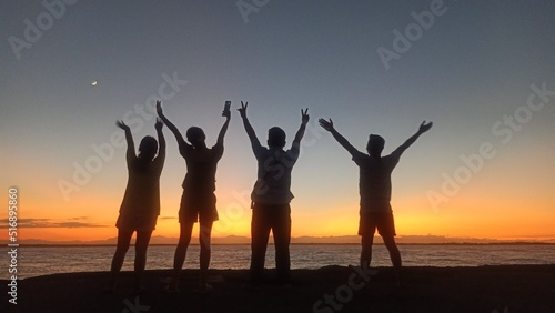Individuals in silhouettes jumping on the beach