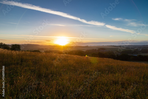 Spectacular sunrise in the rolling hill landscape in the south of Limburg with a view on the meadows and on a row of poplar trees, creating the feeling of being in the Siena Province of Italy. © KimWillems