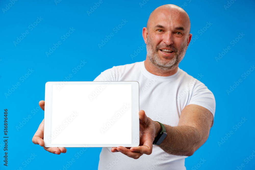Happy caucasian middle-aged man showing tablet`s screen over blue background Happy caucasian middle-aged man showing tablet`s screen over blue background