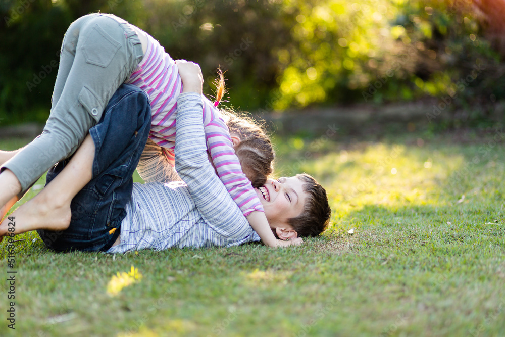 Brother and sister play fighting together on lawn in garden Stock Photo | Adobe Stock