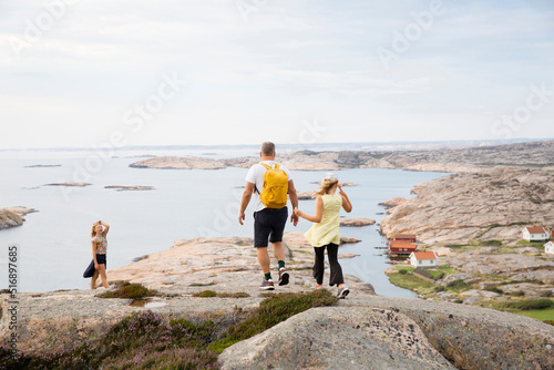 Family walking on rocks by coast photo