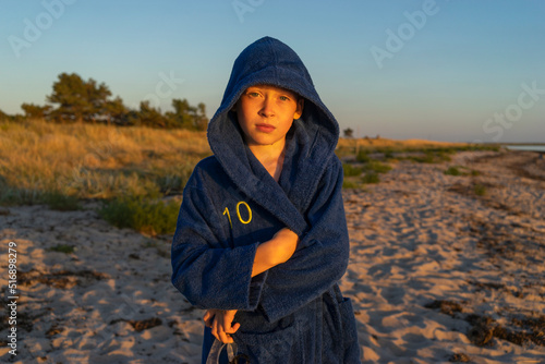 Boy in hooded bathrobe on beach at sunset photo
