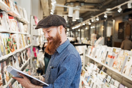 Bearded man reading magazine in store photo
