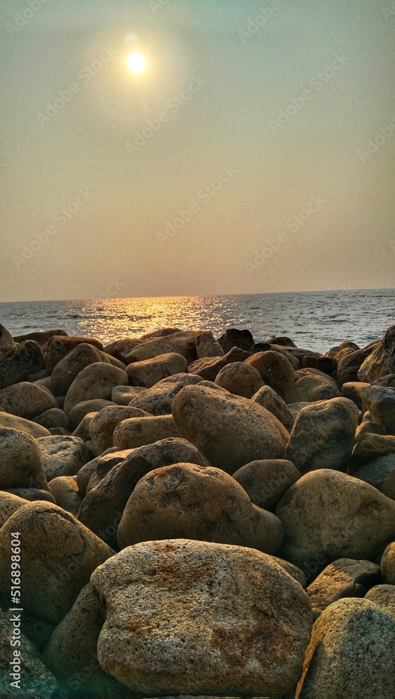 Rocky beach shore under the bright sun and rocks act as sea walls