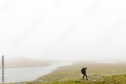 Woman with backpack hiking in fog photo