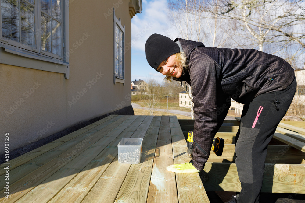 Mature woman drilling and building deck Mature woman drilling and building deck