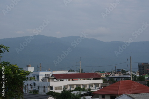 Top view of buildings in Chiang Mai city with a background of a mountain and blue cloudy sky in Chiang Mai, Thailand © Mart