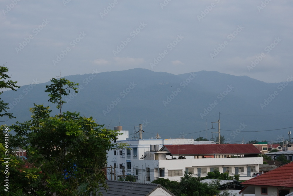 Top view of buildings in Chiang Mai city with a background of a mountain and blue cloudy sky in Chiang Mai, Thailand