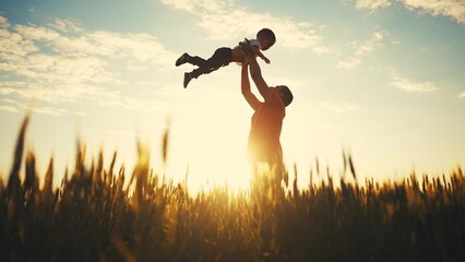 father playing with son in the park. dad throws baby up into the sky silhouette in the field in nature in the park. happy family kid concept. father dream day. baby boy playing with father silhouette