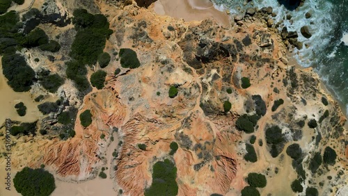 Aerial shot of cliffs, beaches and ocean. In the distance, people on the beach. Praia Marinha, Lagoa, Algarve, Portugal