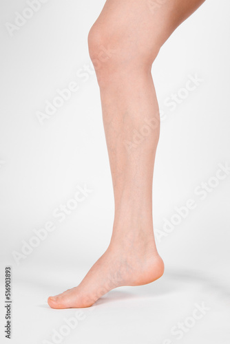 Barefoot and legs isolated on white background. Closeup shot of healthy beautiful female feet. Health and beauty concept. Side view of human foot ream with neutral manicure or pedicure. Sole of foot.