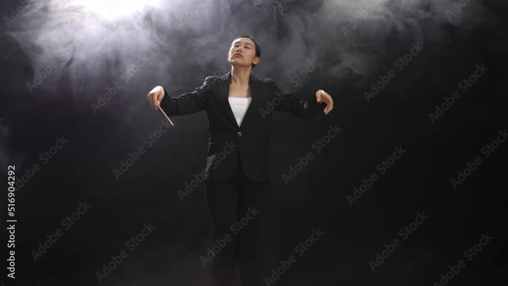Asian Conductor Woman Holding A Baton Closing Her Eyes And Showing Gesture In The Black Studio With Fog
Asian Conductor Woman Holding A Baton Closing Her Eyes And Showing Gesture In The Black Studio With Fog
