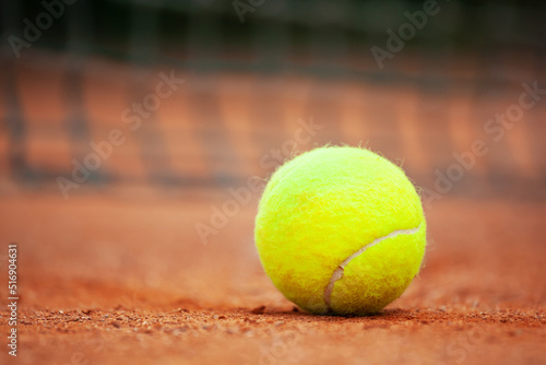 Yellow tennis ball lies on the clay court close up. © Dmytro Panchenko