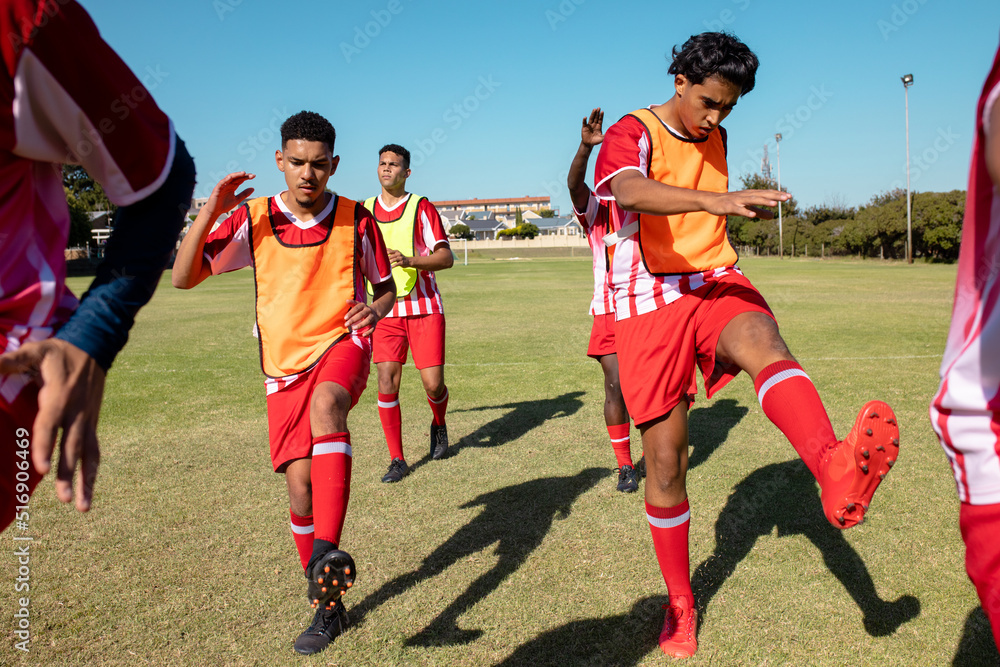 Obraz premium Male multiracial athletes stretching legs while exercising on playground against clear sky in summer