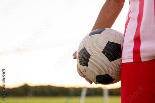 Midsection of caucasian male soccer player in red jersey holding ball standing against clear sky © wavebreak3