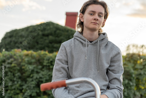 Young man in hoodie sitting on bicycle photo