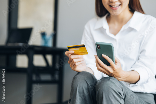 Beautiful woman holding a credit card, she uses a credit card to pay for goods and services online, the concept of using a credit card for online shopping, ordering goods and services on the website.