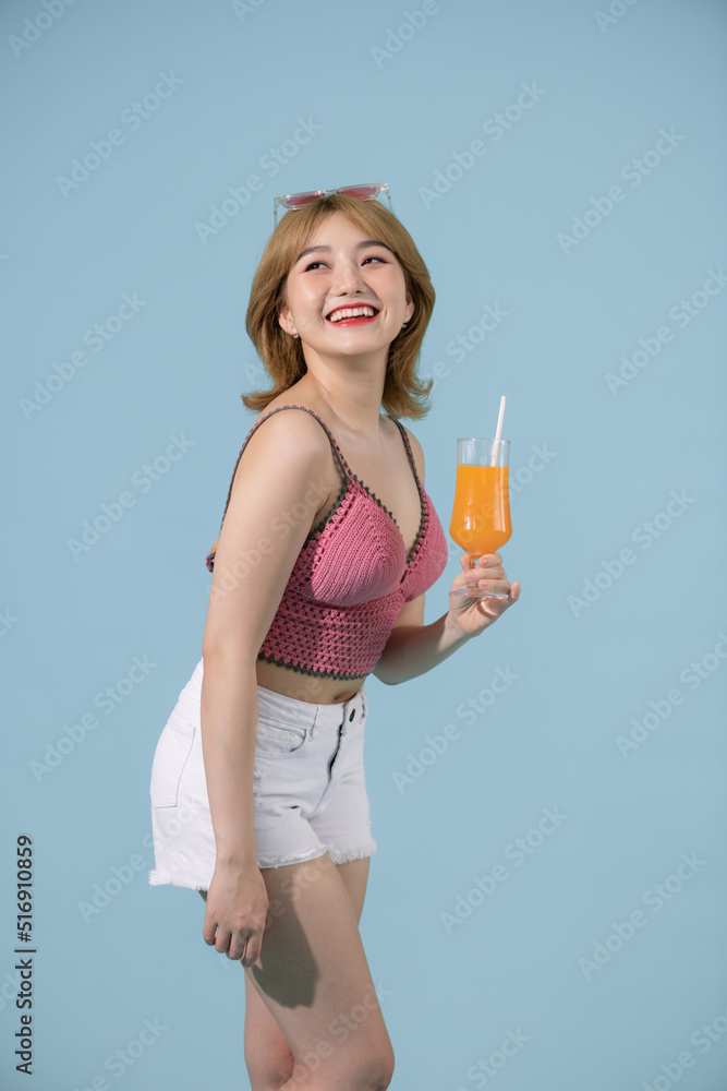 Happy Asian woman in summer casual clothes with a glass of fresh fruit juice drink on pastel blue background Happy Asian woman in summer casual clothes with a glass of fresh fruit juice drink on pastel blue background
