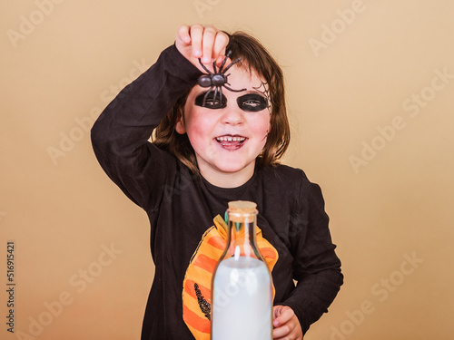 happy elementary girl shows a spider disguised as a skeleton wearing a T-shirt with a pumpkin designhalloween party photo