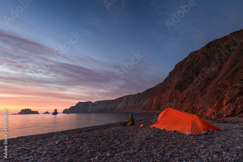 Senior woman by tent sitting on beach at sunset photo