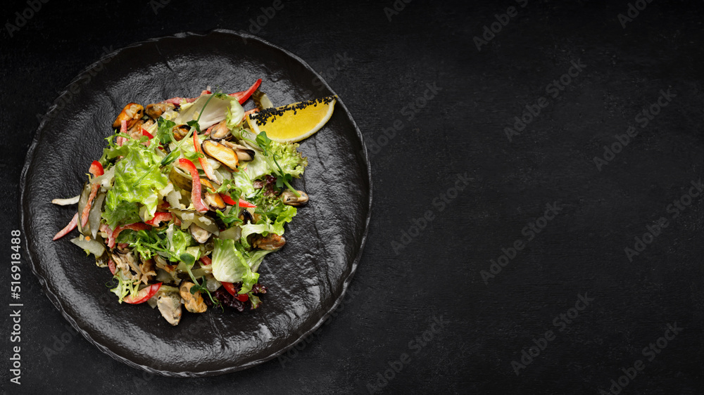 Salad with mussels, on a black plate