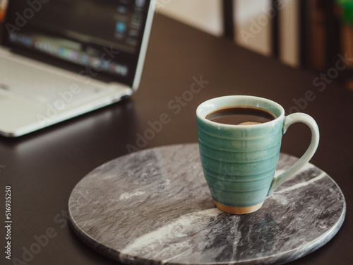 A cup of coffee on a marble board. Home office, coffee time, laptop.