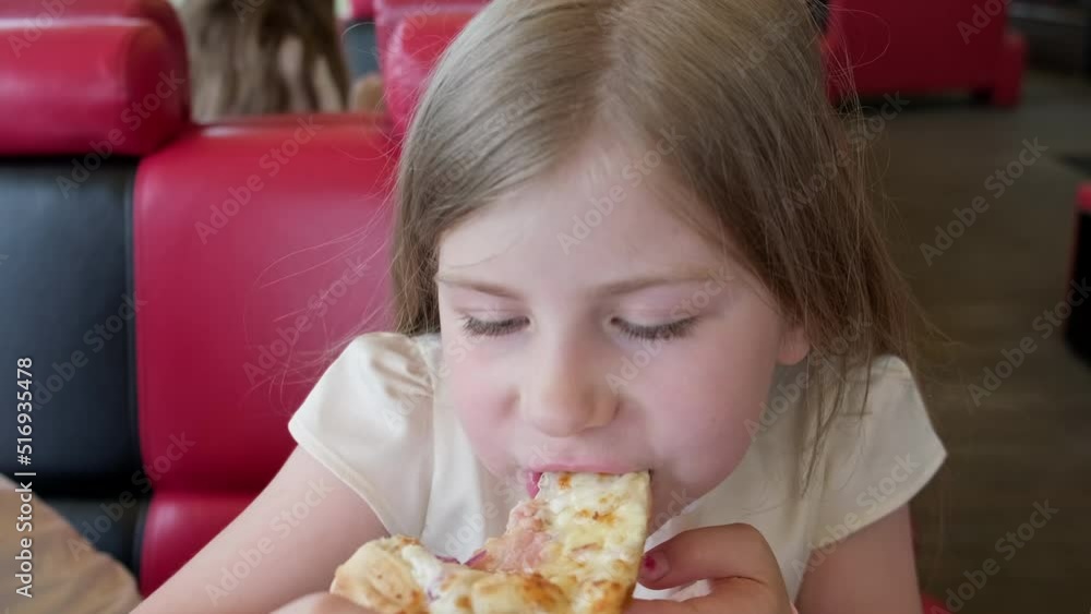 Child eating pizza with a lot of cheese. Little girl eating pizza with great pleasure indoors. Kid enjoy eating pizza with hands. Close-up in 4K, UHD Child eating pizza with a lot of cheese. Little girl eating pizza with great pleasure indoors. Kid enjoy eating pizza with hands. Close-up in 4K, UHD