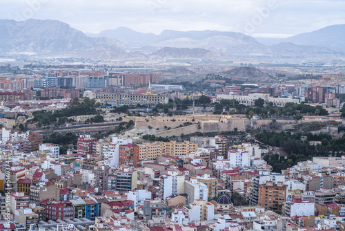 contemporary buildings in the city center against the overcast mountains © Piotr