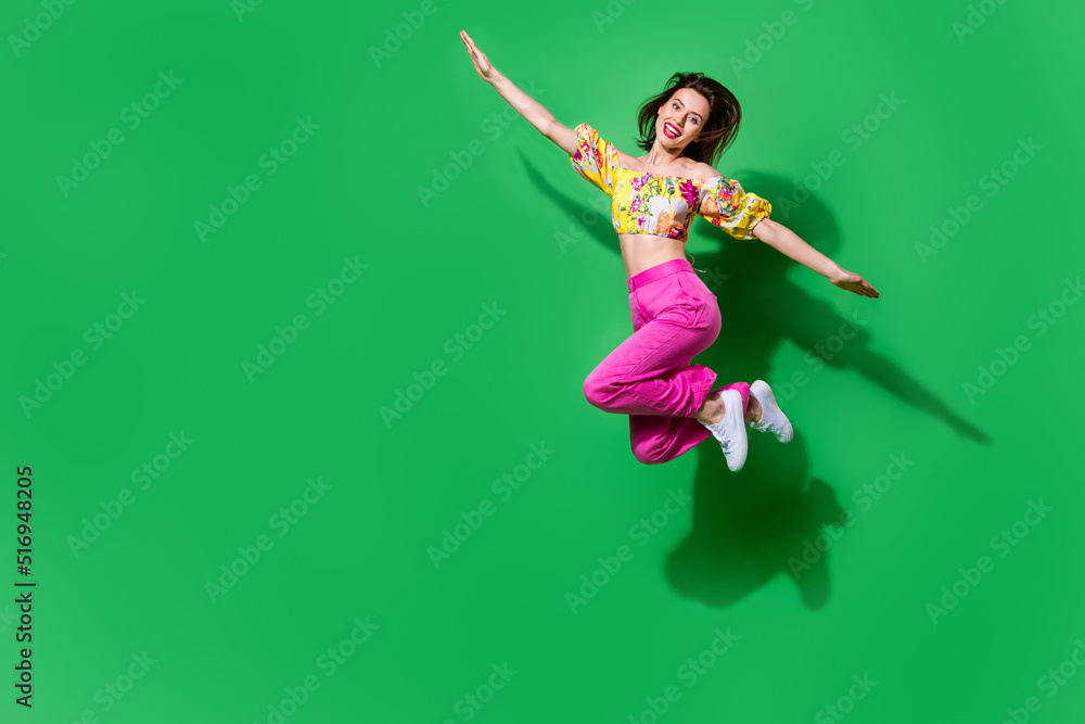 Full length photo of dreamy childish girl dressed off shoulders top jumping high arms sides empty space isolated green color background Full length photo of dreamy childish girl dressed off shoulders top jumping high arms sides empty space isolated green color background