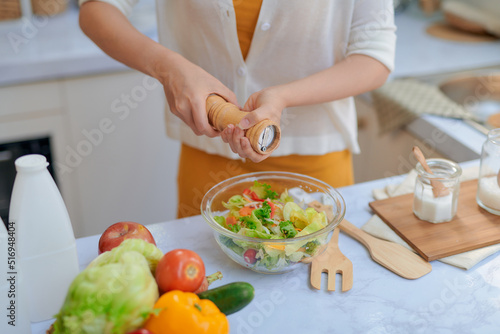 Pretty young woman chef putting salt in a salad