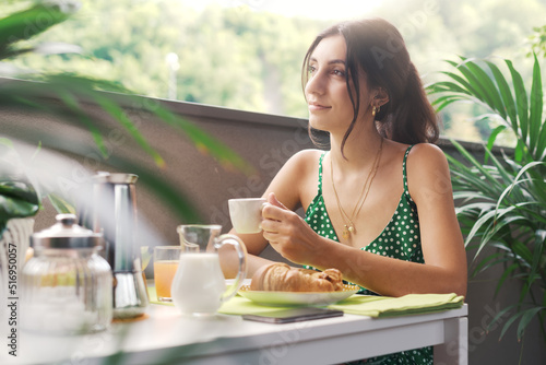 Fotografia Happy woman having breakfast on the balcony