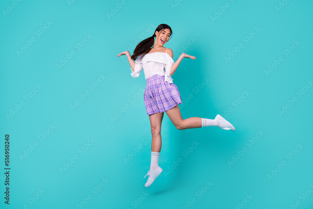 Full size photo of cheerful carefree lovely thai person jumping have fun isolated on cyan color background Full size photo of cheerful carefree lovely thai person jumping have fun isolated on cyan color background