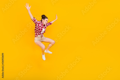 Full length photo of overjoyed cheerful girl enjoy free time jumping travel isolated on yellow color background