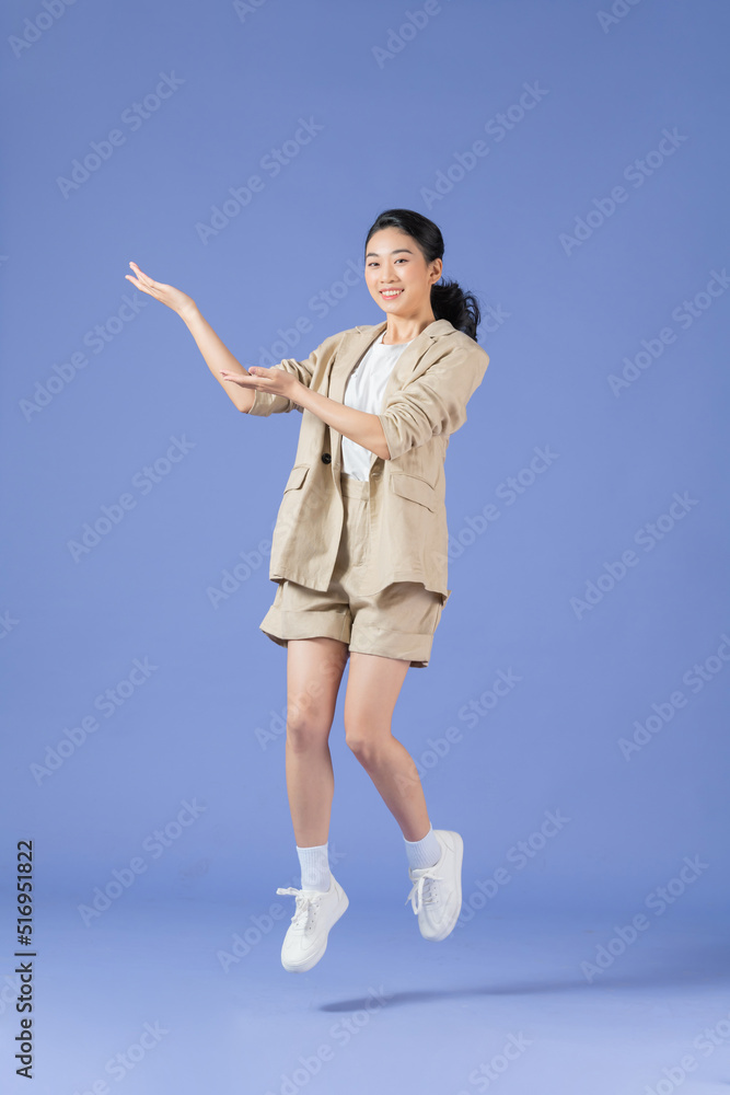 young happy positive smiling woman jump with hands showing nothing on lilac color background young happy positive smiling woman jump with hands showing nothing on lilac color background