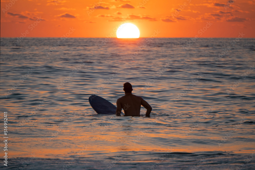 Silhouette of Surfer waiting on the line up for a wave at sunrise or sunset