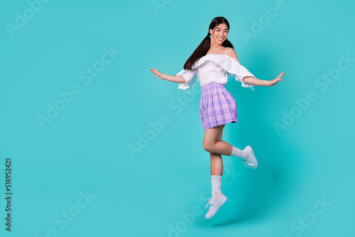 Full body photo of satisfied gorgeous cheerful girl jumping empty space isolated on turquoise color background