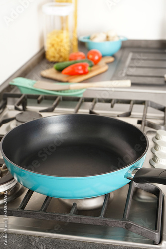 Fotótapéta New frying pan on the stove, fresh vegetables lie on the countertop, vertically