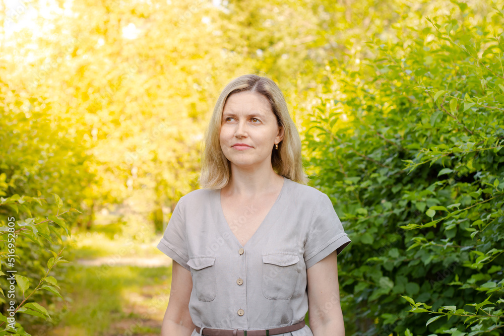 Woman walking in the park and smiling. Modest makeup, looks natural Woman walking in the park and smiling. Modest makeup, looks natural