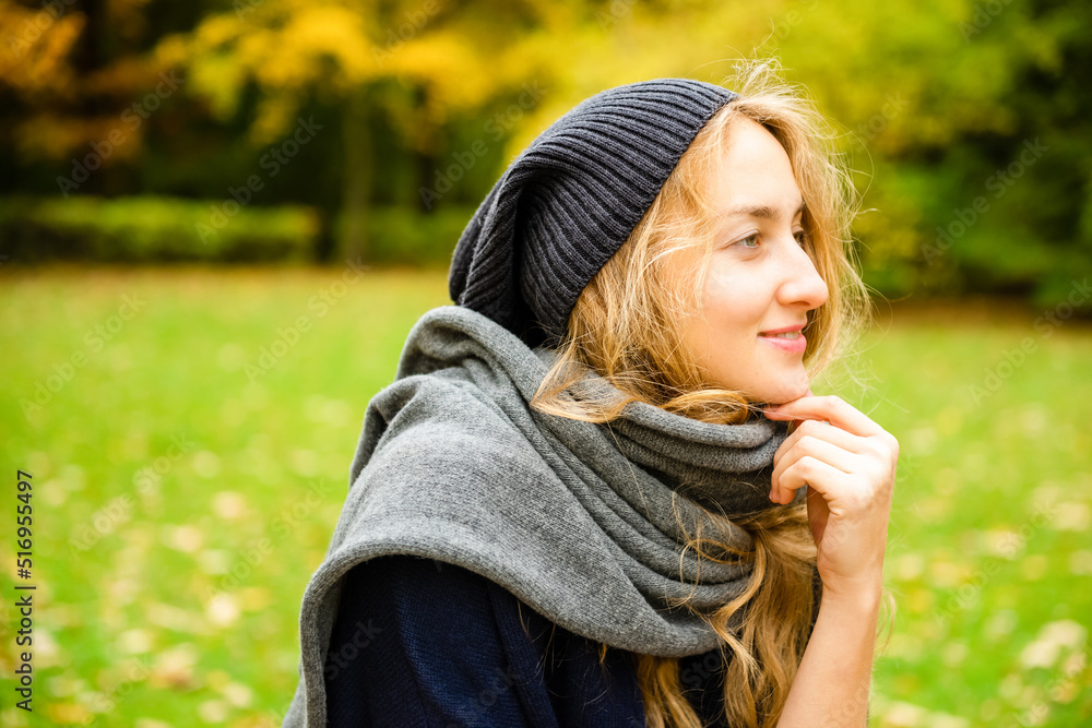 pretty smiling woman wearing knitting hat and scarf thoughtfully looking side outdoor in the city park in fall season pretty smiling woman wearing knitting hat and scarf thoughtfully looking side outdoor in the city park in fall season