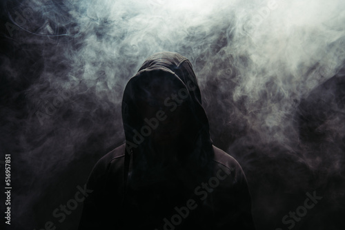 Silhouette of hooligan on black background with smoke photo