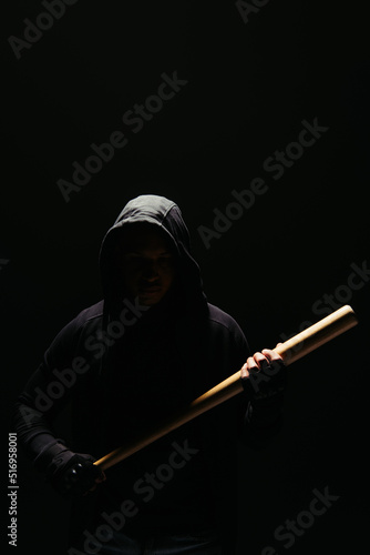 Silhouette of bandit in hoodie holding baseball bat isolated on black