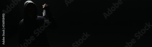 Silhouette of hooligan with knife isolated on black with copy space, banner